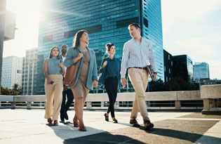 Two business people walking up steps near modern buildings.
